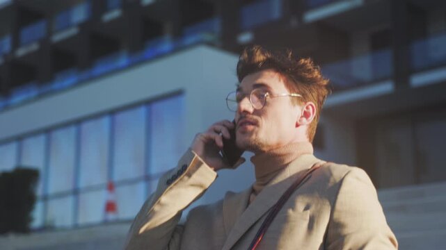 Business professional walking outside during evening, City dweller chatting on cellphone while ascending steps
