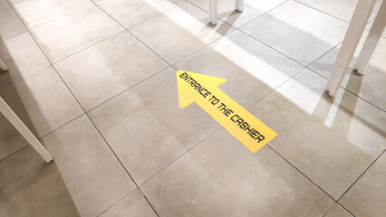 Detailed photo of a sign with text "ENTRANCE TO THE CASHIER" on beige tiled floor at mall