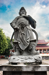 Naklejka premium Traditional Chinese Stone Guardian Statue with Dramatic Low Angle and Blue Sky Background