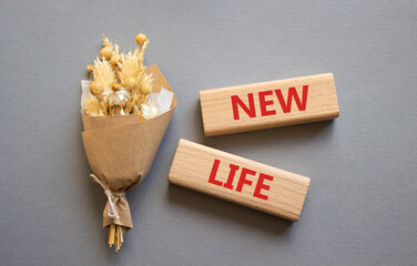 New life symbol. Concept word New life on wooden blocks. Beautiful grey background with bouquet of flowers. Business and New life concept. Copy space