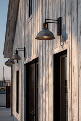 The exterior of a modest building is beautifully illuminated by elegant lighting fixtures as the sun sets, casting a warm glow over the outdoor space