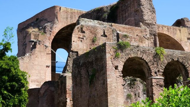 massive ancient roman brick arches walls appears layered different heights weathered surfaces greenery clear blue sky crowns tempio del divo romolo view rome italy empire emperor 