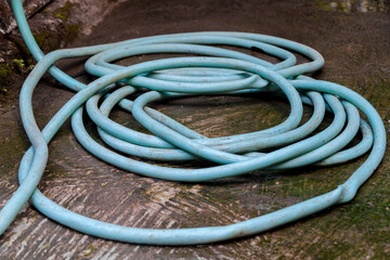Coiled Blue Garden Hose on Wet Ground Outdoors, Flexible Water Hose for Garden Use