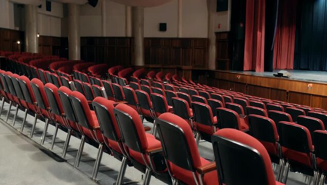 High resolution 4K cinematic footage of an empty theater with rows of red chairs waiting silence performance to begin creating atmosphere symmetry storytelling stock 