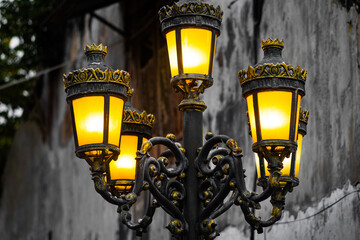 Ornate Vintage Street Lamp with Five Glowing Lanterns on Old Wall Background at Night
