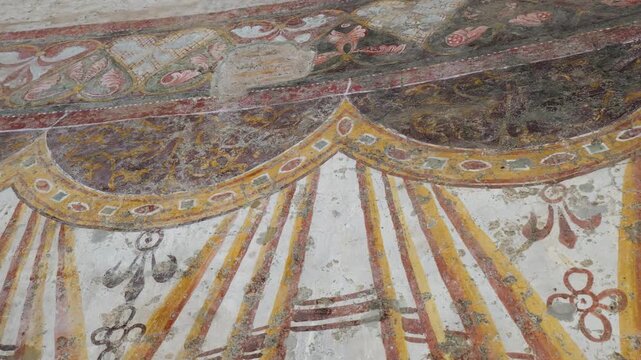 weathered roman fresco fragment ornate draped garlands floral motifs faded tones cracked plaster reflects centuries tempio del divo romolo rome italy empire emperor ancient art 