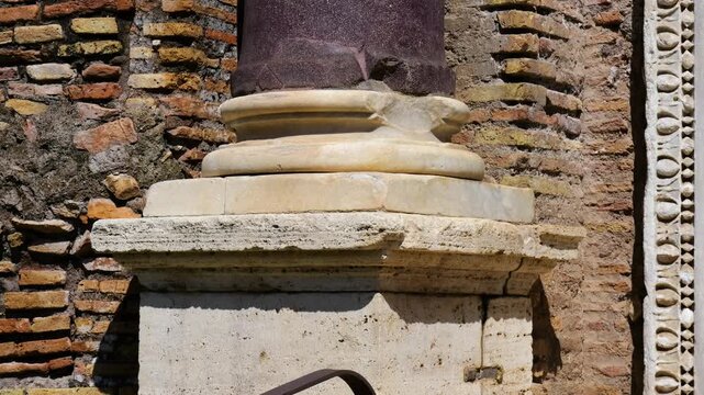 ancient roman column base layered pale marble moldings dark porphyry shaft chips cracks appear tempio del divo romolo reveals up close view rome italy empire emperor 