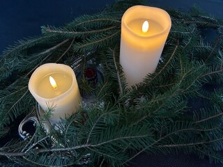 Christmas decoration with candle and christmas tree. Two lit candles surrounded by fir branches creating cozy Christmas atmosphere