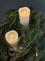 Christmas decoration with candle and christmas tree. Two lit candles surrounded by fir branches creating cozy Christmas atmosphere