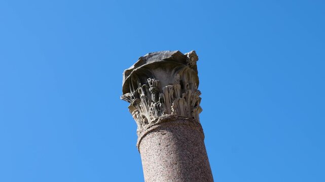 ancient roman stone column intricately carved corinthian capital weathered surfaces silhouette sharply against clear blue sky foro di cesare up close upward view rome italy empire 