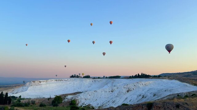 DENIZLI, Turkey, May 6, 2023: Balloons and travertine pools at dawn in Pamukkale. Balloons fly over the snow-white "Cotton Castle". Thermal springs. 4К