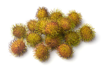 scattered pile of fresh yellow and green rambutans isolated white background, reddish hairy spines and textured fruit skins with soft lighting in top view