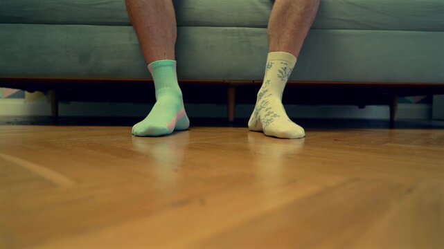 Different socks in legs. Mismatched multicolored socks on feet man. Men's legs in Different socks as symbol of down syndrome. Down syndrome awareness concept. Wear Mismatched Socks. Disabled person.