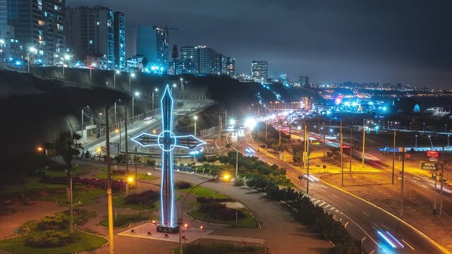 Cars driving on a busy coastal highway at night in lima, peru, with the glowing cross monument