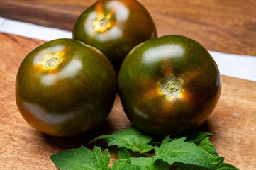 Obraz premium Fresh ripe sweet reddish brown and green kumato tomatoes on board