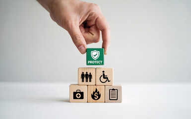 Hand Placing Green Protect Block on Stack of Wooden Insurance Icons