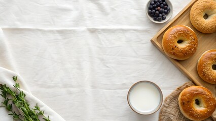 Freshly Baked Bagels With Sesame Seeds Served With Milk And Blueberries On A White Tablecloth