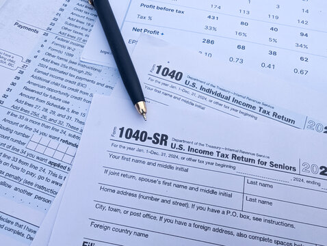 US Form 1040 and Form 1040-SR for senior citizens with pen on financial statement sheets for tax preparation concept