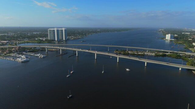 Long bridge crossing wide river with boats marina and waterfront buildings near Daytona Beach Florida on clear sunny day