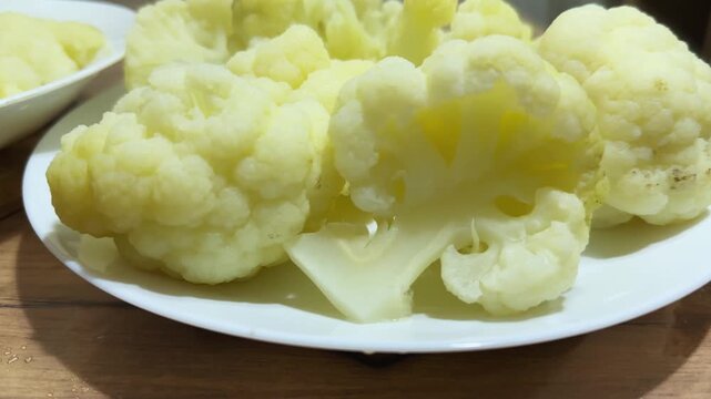 Boiled cauliflower pieces on two plates, front view close-up
