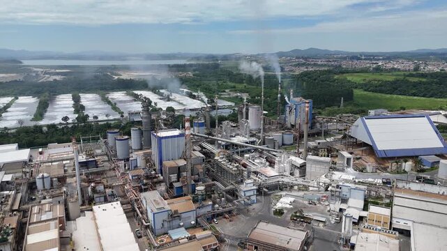 Vista a&eacute;rea mostra ind&uacute;stria de papel e celulose integrada a um amplo complexo industrial com caldeiras e chamin&eacute;s em funcionamento.