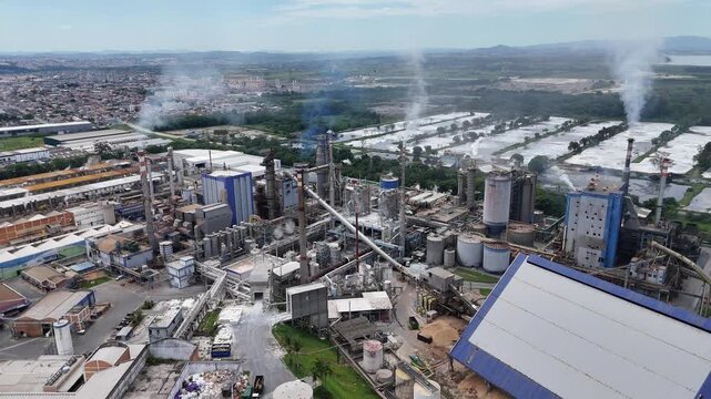 Filmagem a&eacute;rea de planta industrial de papel e celulose destacando produ&ccedil;&atilde;o, chamin&eacute;s ativas e rela&ccedil;&atilde;o entre ind&uacute;stria e meio ambiente.