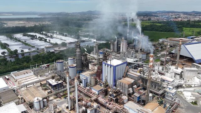 V&iacute;deo de drone mostrando ind&uacute;stria de papel e celulose em opera&ccedil;&atilde;o, com chamin&eacute;s, caldeiras e estruturas industriais integradas ao ambiente.