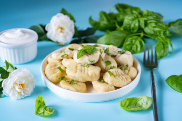 Potato nyoches on a white plate on a blue background. Potato dumplings for lunch. Close-up