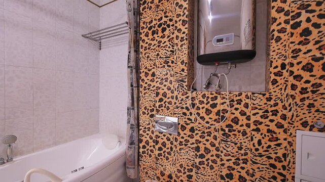 Bold bathroom with leopard-print tiles, white sink, bathtub, mirror with lights, towel rail, neutral tiled walls, modern fixtures, striking animal-pattern accents