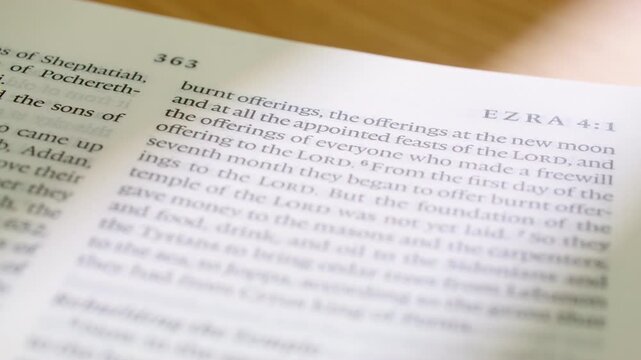 Macro footage of a modern English Bible as pages turn to Ezra book. Detailed printed text, smooth page motion, and soft lighting make it ideal for faith, study, worship, and teaching projects