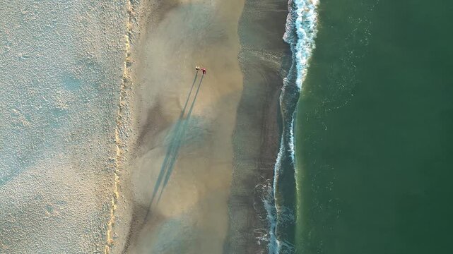 A couple walks along the beach at sunrise, in Oak Island, North Carolina