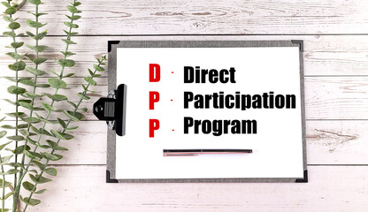 Clipboard with text direct participation program and pen on white wooden background with green plant