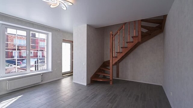 spacious room with a wooden staircase, large panoramic windows, neutral-toned walls, a radiator beneath the windows, and a modern ceiling light fixture