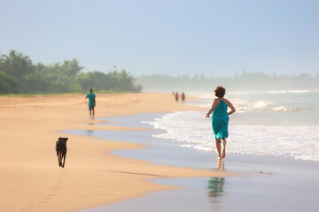 Woman and dog enjoying morning jog on calm tropical beach