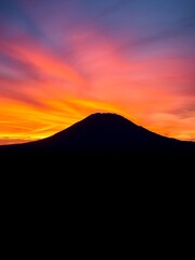 Majestic flat-topped mountain silhouetted against a fiery orange and purple sunset, casting long shadows across the plain, africa,  mesa