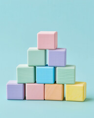 Fototapeta premium Pastel Wooden Blocks Stacked in Tower on Blue Background, minimal composition of pastel-colored wooden blocks arranged in pyramid shape against clean blue background