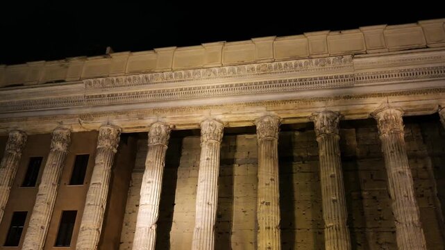 warmly illuminated night classical roman portico tall fluted corinthian columns carved friezes ornate stand piazza di pietra / temple hadrian view rome italy empire emperor 