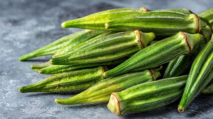 Pile of fresh, ripe green pods rests upon a textured, muted background surface