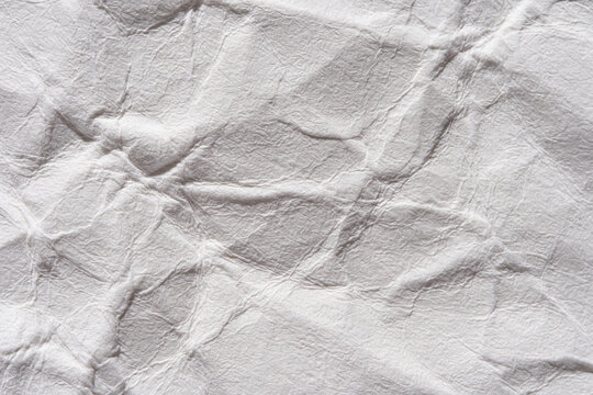 Close-up of crumpled white paper texture with wrinkles and creases for background or design use.