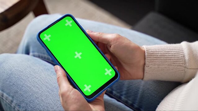 Woman holding a smartphone with a green screen for chroma key compositing, perfect for app demonstrations or content display.