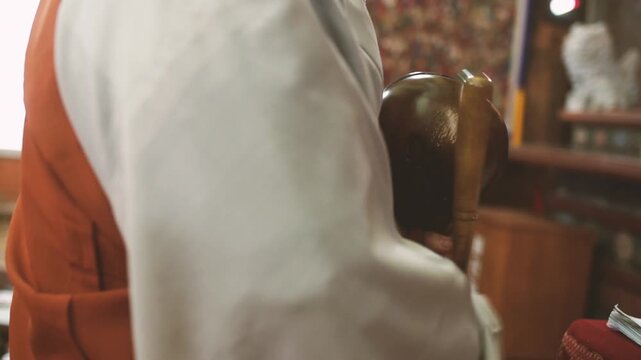 Buddhist Monk Striking Wooden Fish Moktak during Chanting Ritual at Korean Temple - 한국 전통 사찰에서 목탁을 두드리며 예불과 염불을 집전하는 스님의 뒷모습