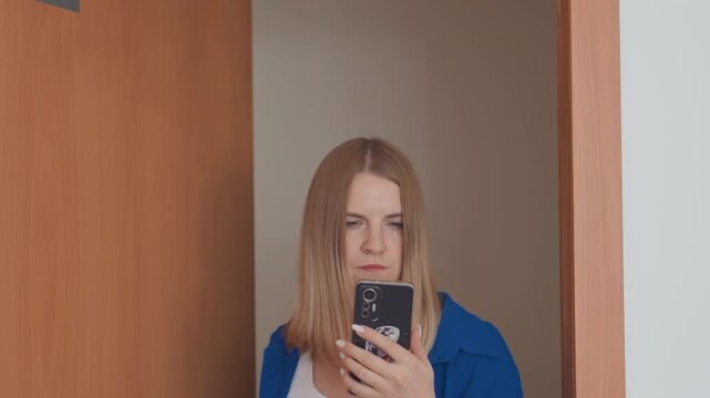 woman peeking from doorway with phone, private message reading, subtle smile, long straight hair, blue jacket, wooden door, indoor hallway, closeup and medium shots, soft natural light, voyeuristic
