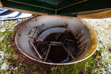 Round fiberglass chamber in turf holds agitated wastewater, PVC manifolds, hoses, and a vented...