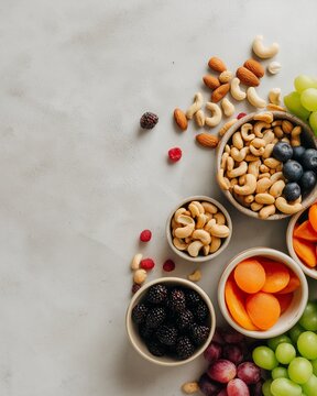 Fruit and nut arrangement on a light surface with various bowls filled with snacks in the afternoon