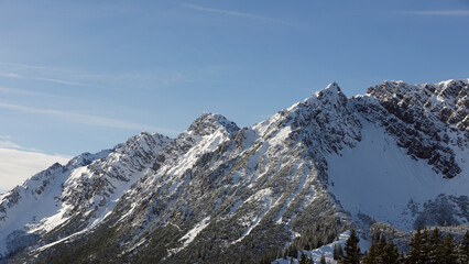 Beautiful panorama of high rocky mountains with snowy peaks against the blue sky and clouds. Brandnertal, Austria