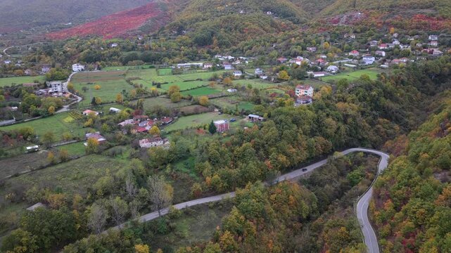 Aerial video of a road and farmland surround the outskirts of Bajram Curri beneath the dramatic Albanian Alps.