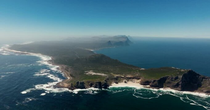 Aerial drone zoom in to Cape of Good Hope in South Africa. Coastline cliffs with ocean beach and green terrain on a sunny clear day. Perfect for travel, tourism, nature, and documentary footage