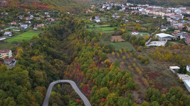 Aerial video of a road and farmland surround the outskirts of Bajram Curri beneath the dramatic Albanian Alps.