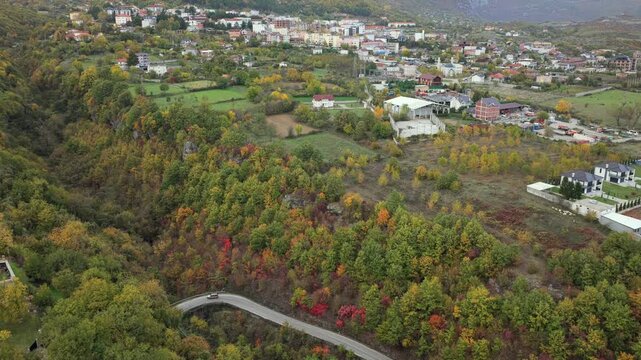 Aerial video of Bajram Curri, showing homes, farmland and the town center set against the steep forested slopes and rugged peaks of the Albanian Alps. 