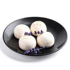 Three delicate balls of creamy white chocolate adorned with vibrant lavender flowers, elegantly arranged on a sleek black plate, creating a striking contrast.
